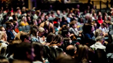 A diverse crowd seated in an auditorium, engaged in an indoor event.