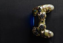 Camouflage-themed game controller emitting blue light on a dark background, perfect for gaming content.