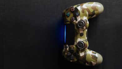 Camouflage-themed game controller emitting blue light on a dark background, perfect for gaming content.