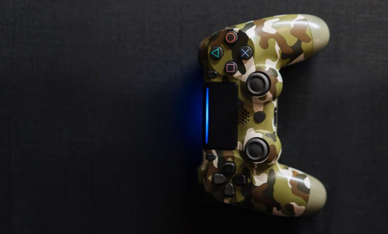 Camouflage-themed game controller emitting blue light on a dark background, perfect for gaming content.