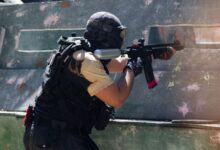 A person engaged in an intense paintball game aiming to hit opponents outdoors.