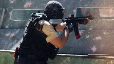 A person engaged in an intense paintball game aiming to hit opponents outdoors.