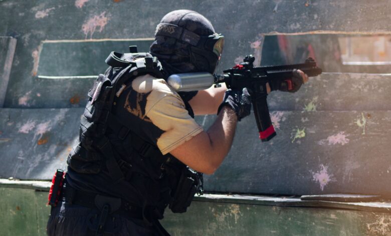 A person engaged in an intense paintball game aiming to hit opponents outdoors.