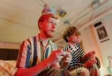 Two men playing video games with controllers and having fun in a cozy room.