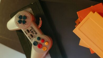 A vintage 8-bit game controller with colorful buttons next to classic game cartridges.