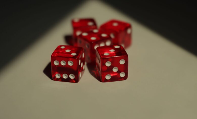 Five red dice with white dots photographed on a neutral background.