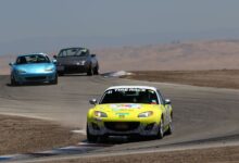 Mazda Miata sports cars racing on a sunny day at Buttonwillow Raceway, California.