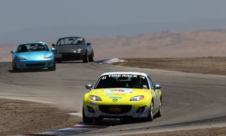 Mazda Miata sports cars racing on a sunny day at Buttonwillow Raceway, California.