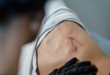 Close-up of a tattoo artist working on an abstract design on a person's back.