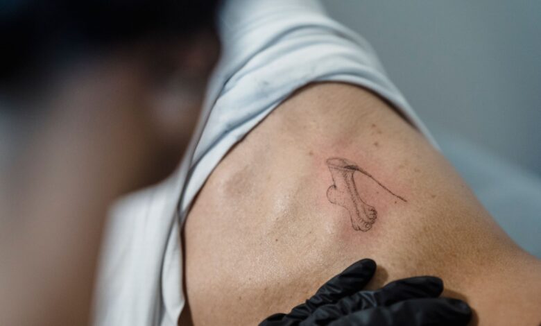 Close-up of a tattoo artist working on an abstract design on a person's back.