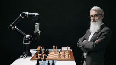 A robotic arm and a bearded man engaged in a strategic chess game highlighting technology and innovation.