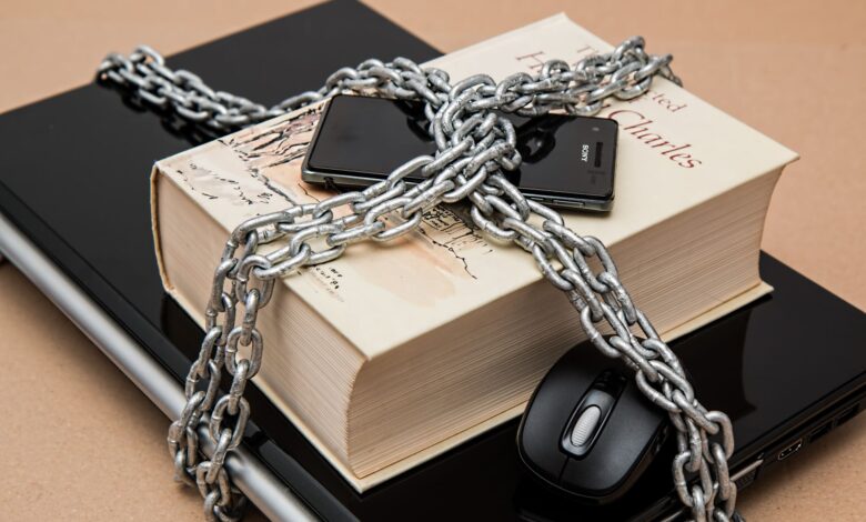 Chain-locked book, phone, and laptop symbolizing digital and intellectual security.