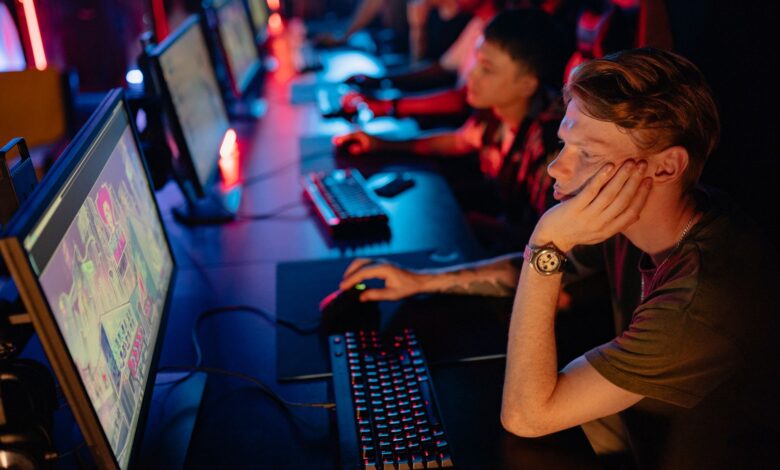 Gamers intensely focused on a computer game during an online esport competition in a dimly lit arena.