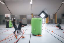Energetic teenagers playing an indoor laser tag game with vibrant inflatables and obstacles.