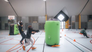 Energetic teenagers playing an indoor laser tag game with vibrant inflatables and obstacles.