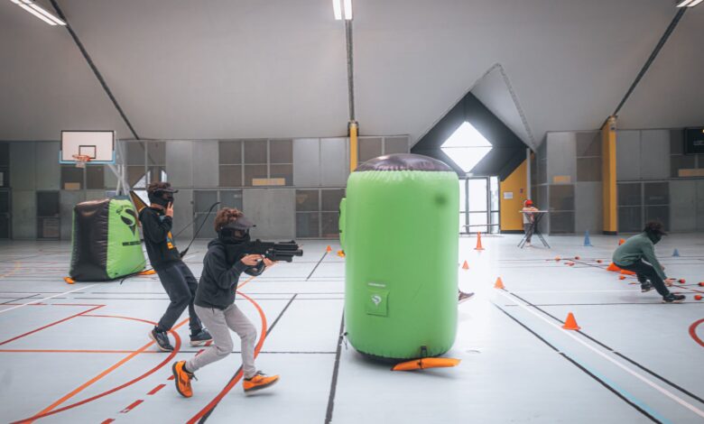 Energetic teenagers playing an indoor laser tag game with vibrant inflatables and obstacles.