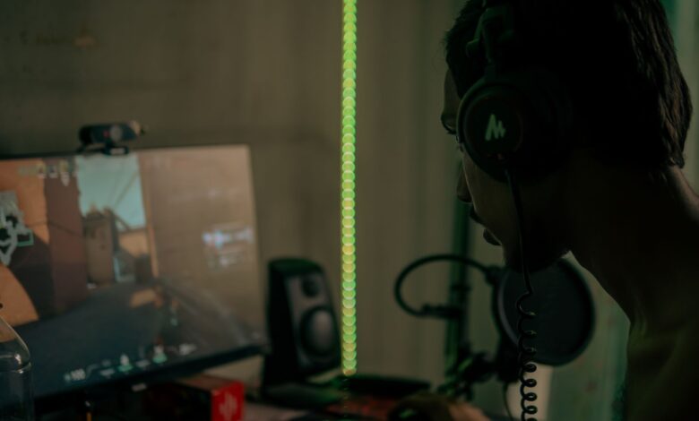 Focused gamer with headset playing a video game on a desktop computer indoors.