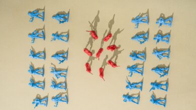 Blue and red toy soldiers arranged on a yellow background with artistic shadows.