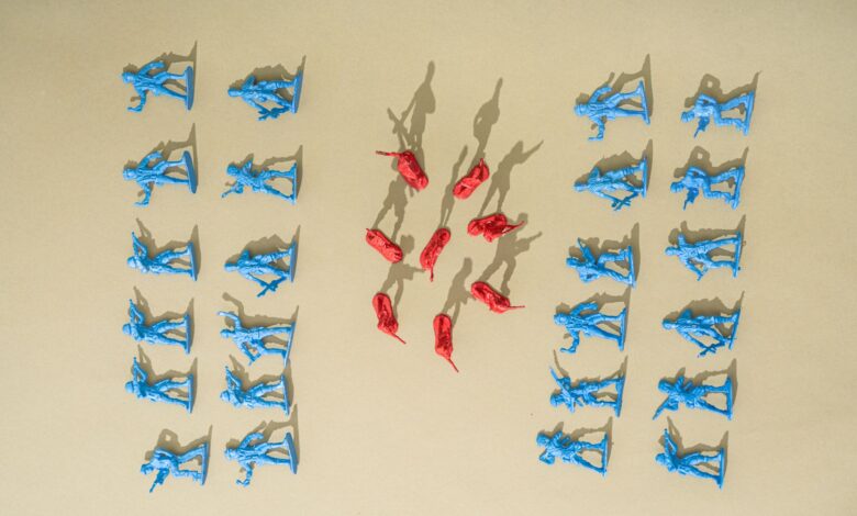 Blue and red toy soldiers arranged on a yellow background with artistic shadows.