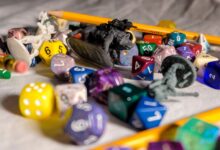High angle of color dices in different shapes scattered on table with small toy animals and pencils during game