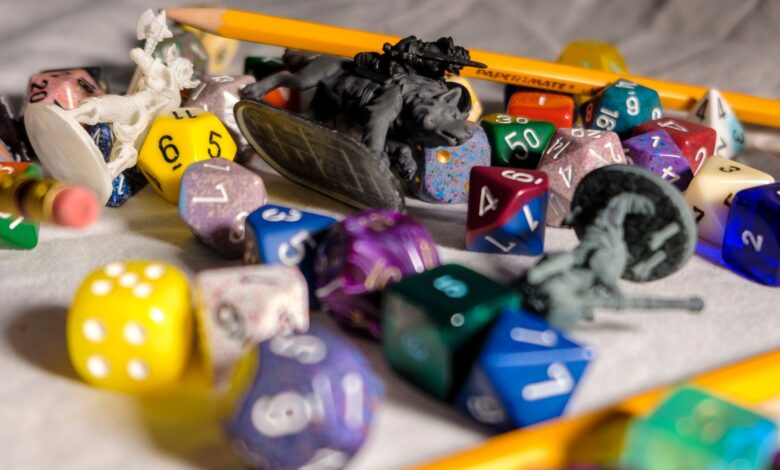 High angle of color dices in different shapes scattered on table with small toy animals and pencils during game