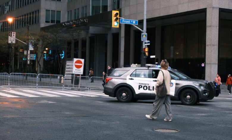 A woman crosses a city street with a Toronto police vehicle nearby.