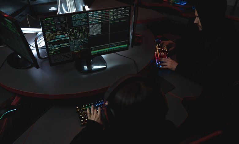 A group of people in a dark room working on computers, related to cybersecurity.