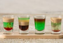 Vibrant layered shots on a wooden tray, Dubai. Perfect for cocktail enthusiasts.