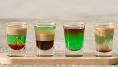 Vibrant layered shots on a wooden tray, Dubai. Perfect for cocktail enthusiasts.