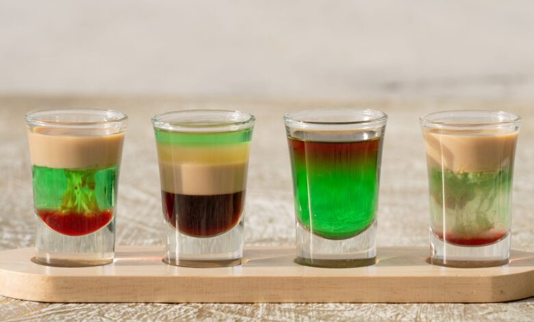 Vibrant layered shots on a wooden tray, Dubai. Perfect for cocktail enthusiasts.