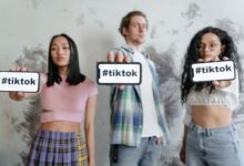 Group of young adults holding phones with #tiktok indoors, showcasing social media culture.