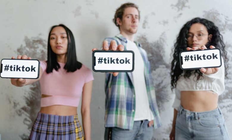 Group of young adults holding phones with #tiktok indoors, showcasing social media culture.