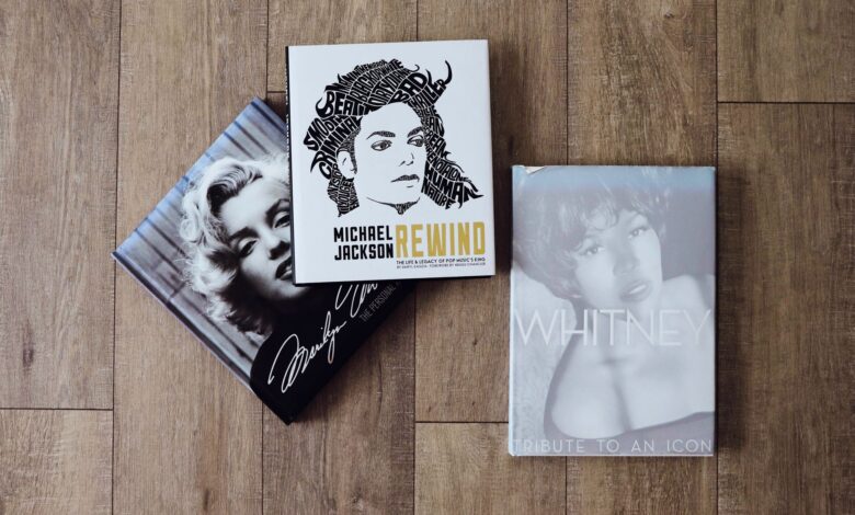 Books featuring Marilyn Monroe, Michael Jackson, and Whitney Houston on a wooden floor.