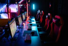 High-tech gaming setup with PCs, RGB lighting, and gaming chairs in a gaming house.