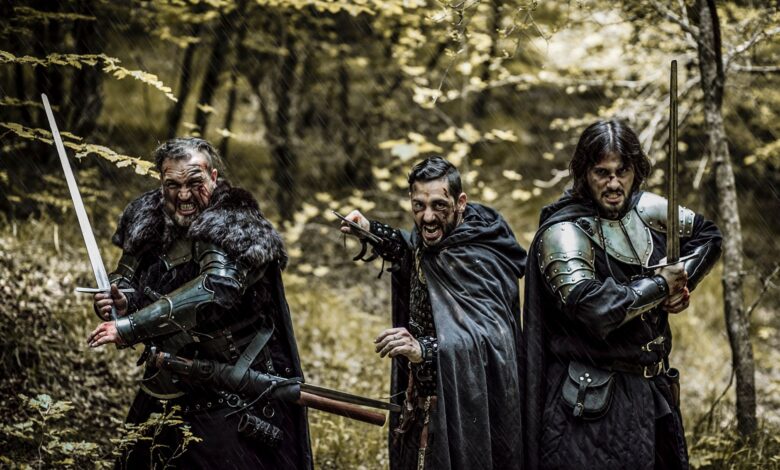 Three men in medieval armor and swords standing in a forest, ready for battle.