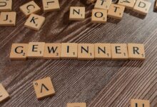 Scrabble tiles forming the word 'Gewinner' meaning winner on a wooden table.