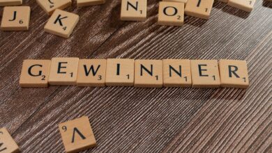 Scrabble tiles forming the word 'Gewinner' meaning winner on a wooden table.