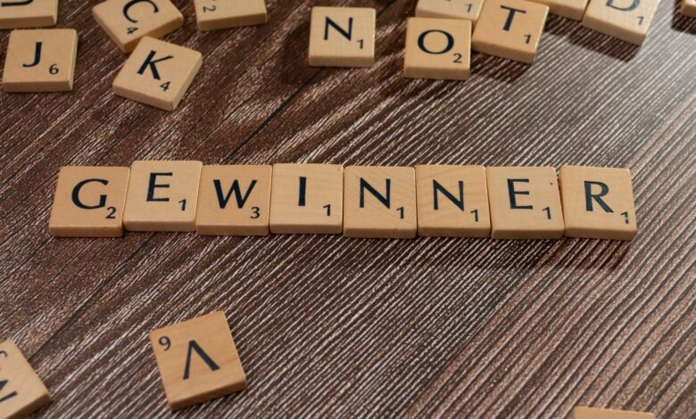 Scrabble tiles forming the word 'Gewinner' meaning winner on a wooden table.