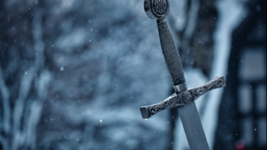 Close-up of a decorative medieval sword standing in a snowy outdoor setting.