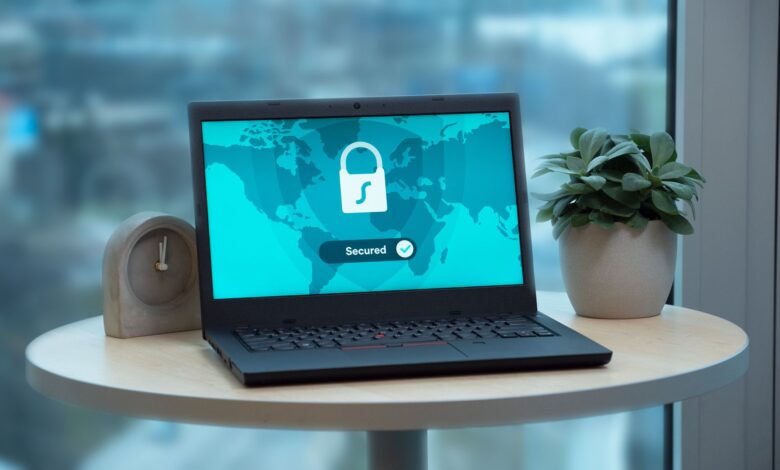 Laptop displaying a security lock icon on a table with a potted plant and clock.
