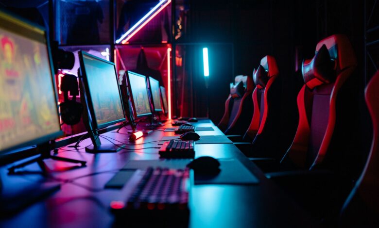 An immersive gaming room with neon lights, computers, and gaming chairs ready for a tournament.