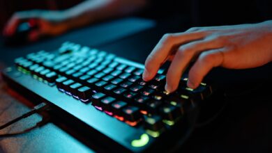 Hands typing on a glowing RGB keyboard during a gaming session indoors.