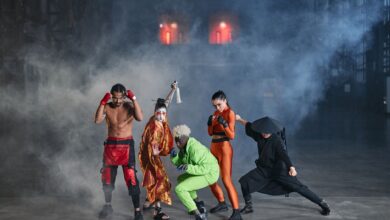 Dynamic group of diverse cosplayers striking action poses in an atmospheric indoor setting with smoke.