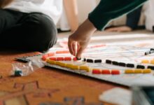 People playing a strategic board game indoors, focusing on hand placing pieces during leisure time.