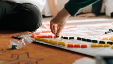 People playing a strategic board game indoors, focusing on hand placing pieces during leisure time.