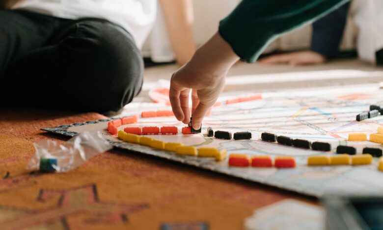 People playing a strategic board game indoors, focusing on hand placing pieces during leisure time.