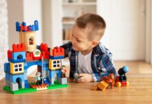 Young boy playing creatively with toy castle and figurines indoors, fostering imagination.