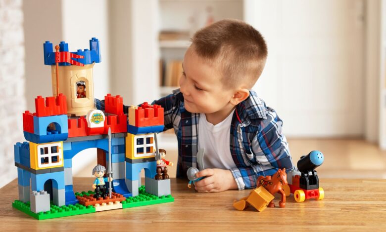 Young boy playing creatively with toy castle and figurines indoors, fostering imagination.