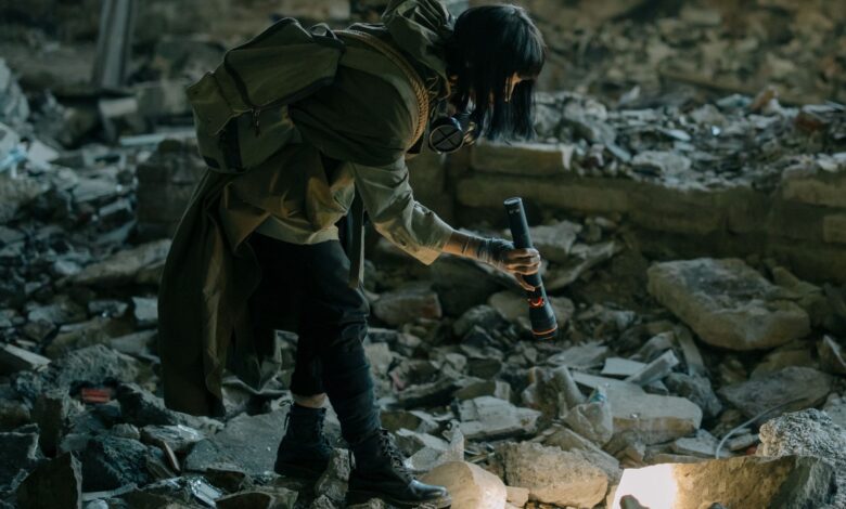 Person exploring an abandoned urban ruin with a flashlight, amidst debris and decay.