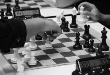 Close-up of a strategic chess match in progress, highlighting focused hands and chess pieces.